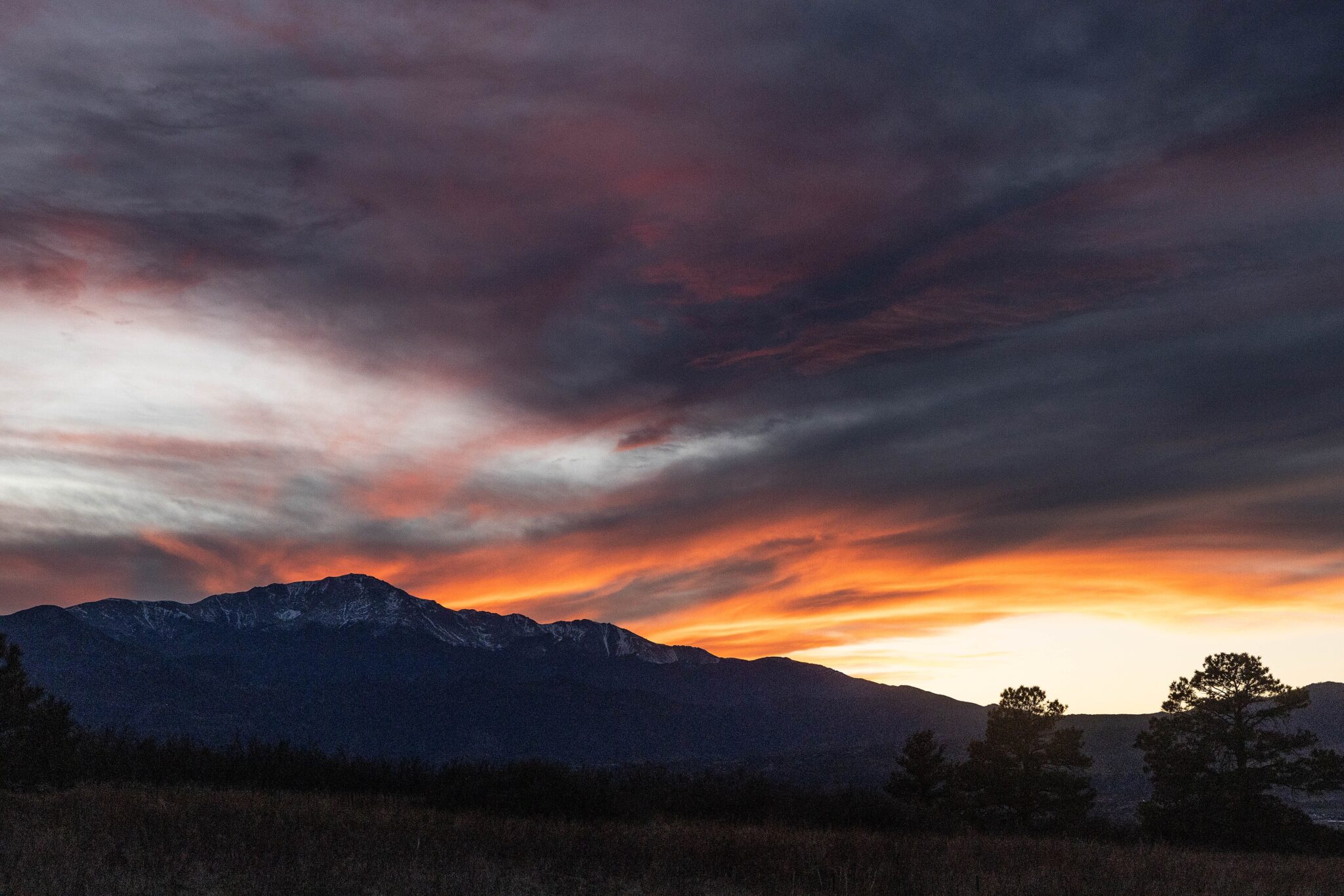 Pikes Peak in silhouette under an orange sunset sky, seen from Palmer Park in Colorado Springs